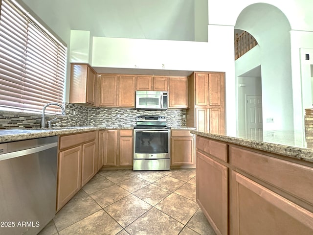 33506 N 24th Dr, Phoenix, AZ 85085 - kitchen featuring stainless steel appliances, a sink, backsplash, light tile patterned floors, and light stone countertops