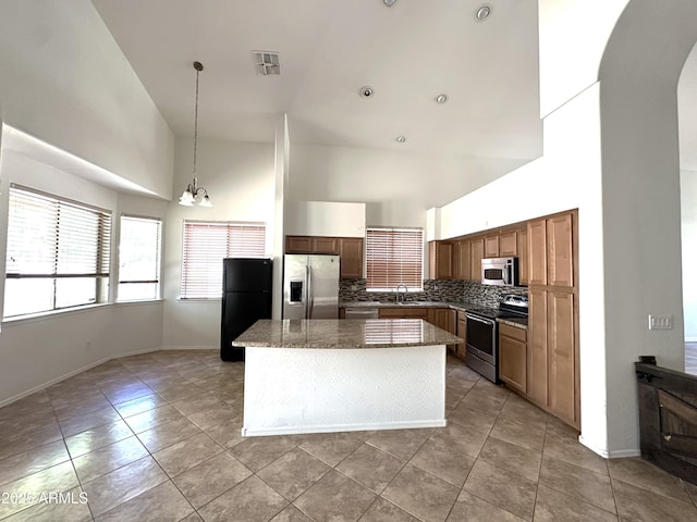 33506 N 24th Dr, Phoenix, AZ 85085 - kitchen with appliances with stainless steel finishes, high vaulted ceiling, decorative backsplash, a center island, and light tile patterned floors