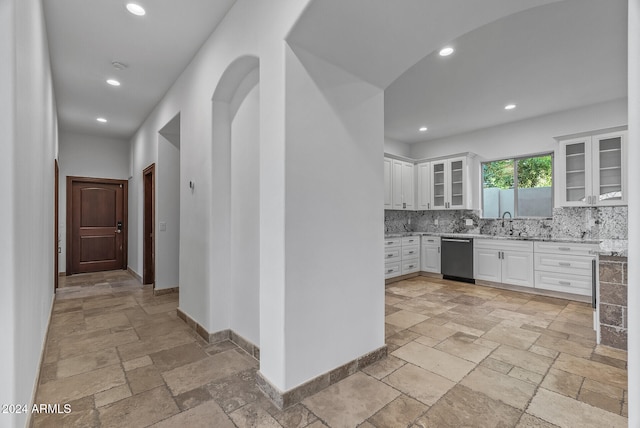 kitchen featuring white cabinetry, backsplash, dishwasher, and light stone counters