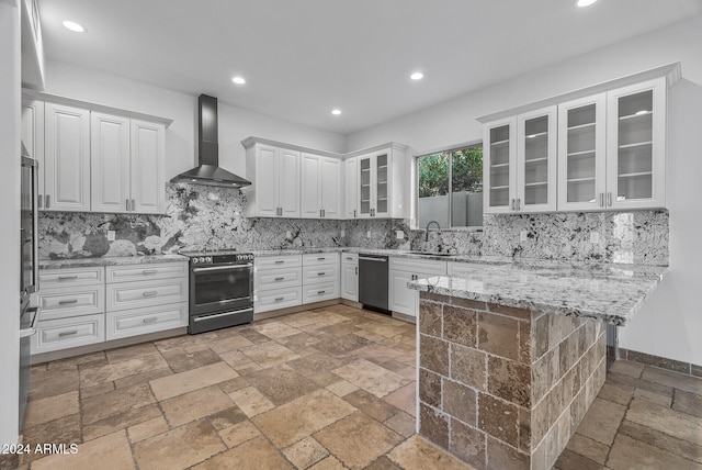 kitchen with wall chimney range hood, white cabinets, appliances with stainless steel finishes, and backsplash