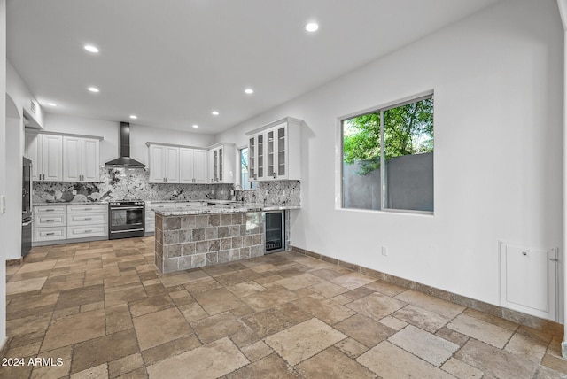 kitchen featuring stainless steel appliances, wall chimney range hood, tasteful backsplash, and white cabinets