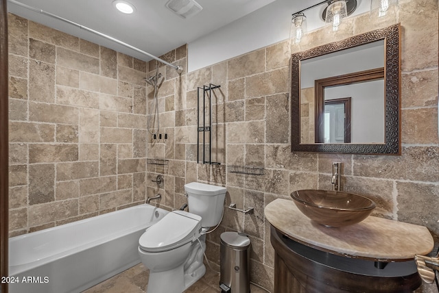 full bathroom featuring vanity, tiled shower / bath combo, toilet, and tile walls