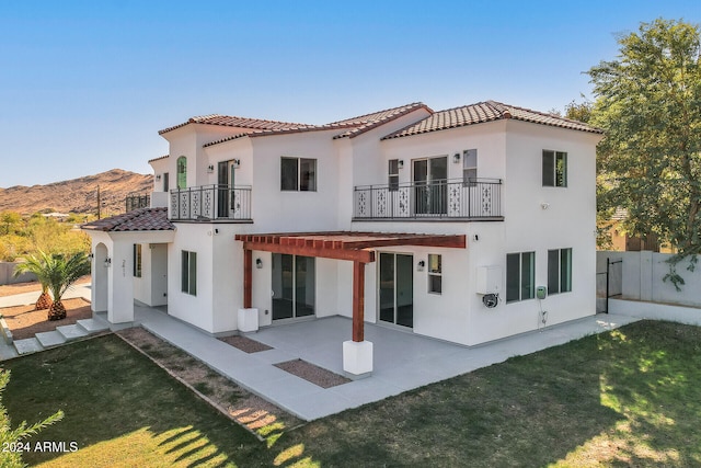 rear view of property featuring a patio, a mountain view, a yard, and a balcony