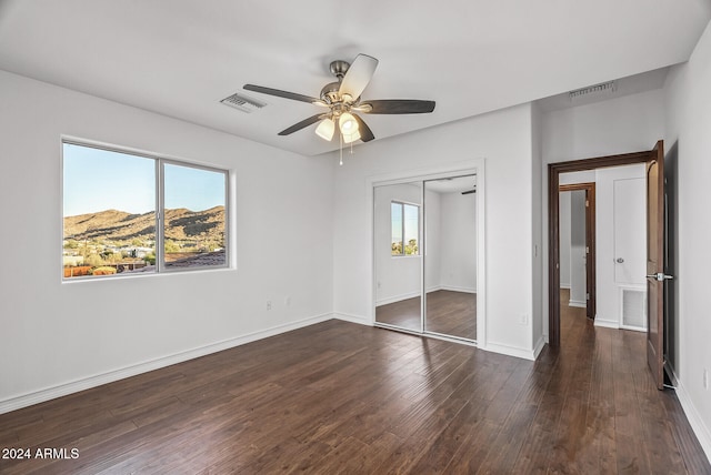 unfurnished bedroom with a closet, dark hardwood / wood-style floors, and ceiling fan