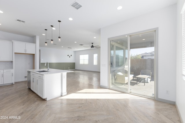 kitchen with light parquet flooring, white cabinetry, sink, and an island with sink