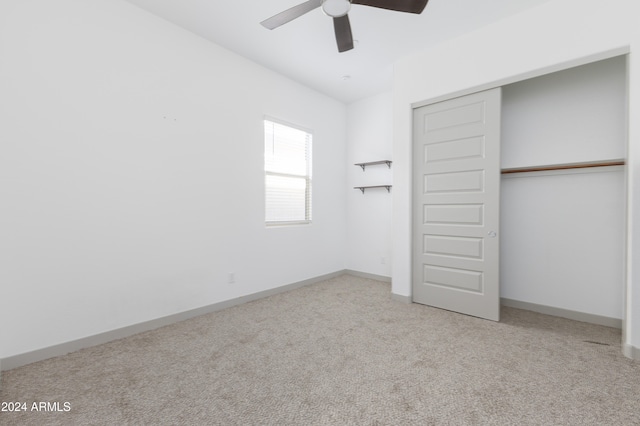 unfurnished bedroom featuring ceiling fan, light colored carpet, and a closet