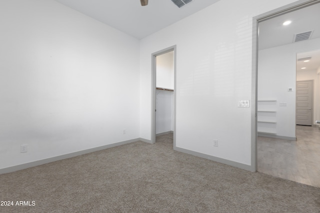 unfurnished bedroom featuring light colored carpet and a walk in closet