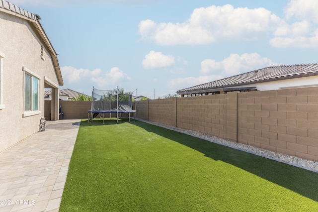 view of yard featuring a trampoline and a patio area