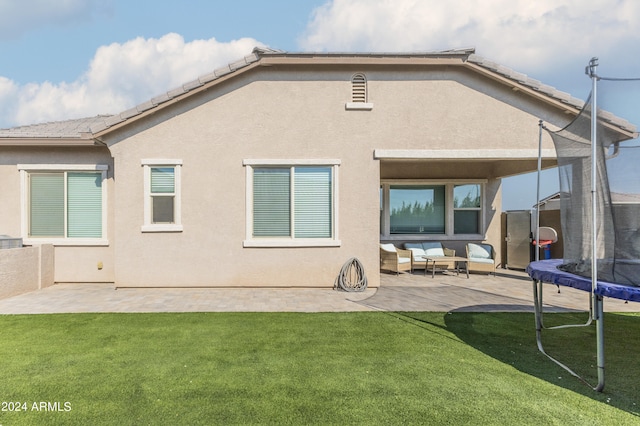 back of property with a patio, a lawn, and a trampoline