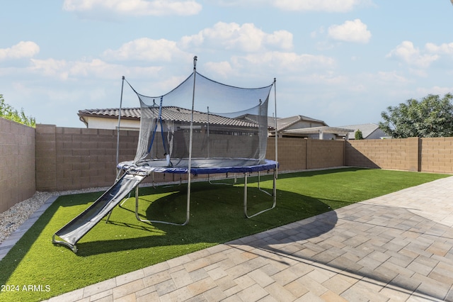 view of yard featuring a trampoline and a patio