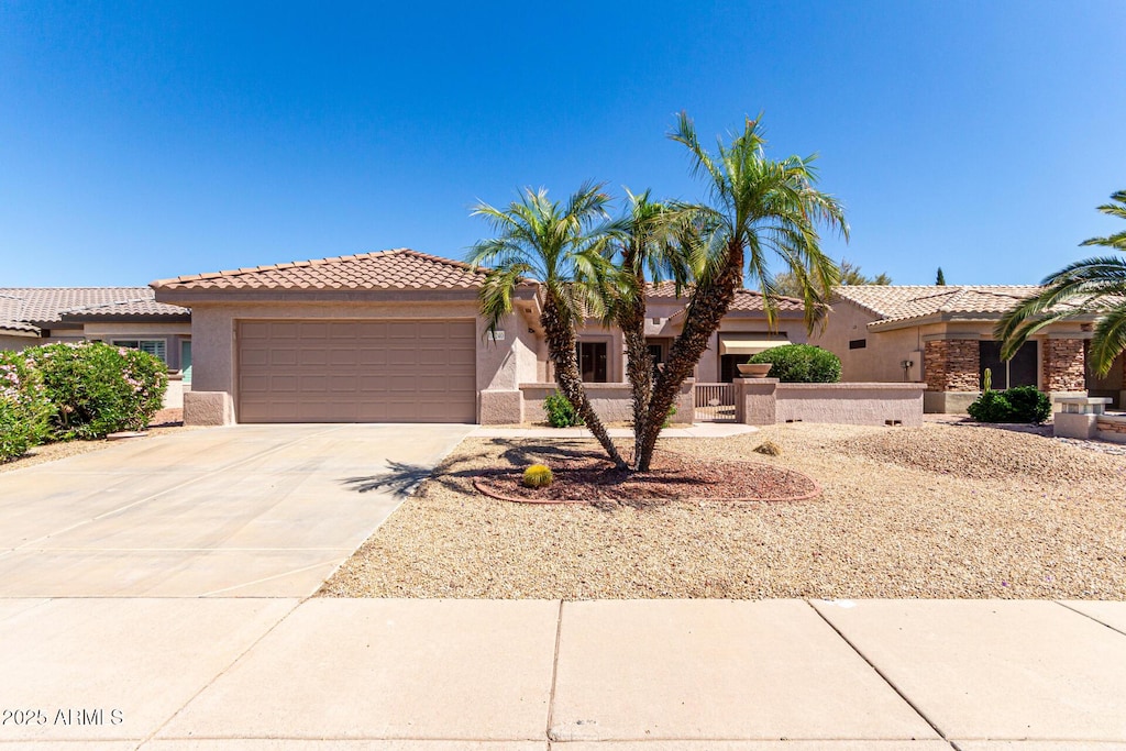 view of front of property featuring concrete driveway, a garage, stucco siding, and a tiled roof