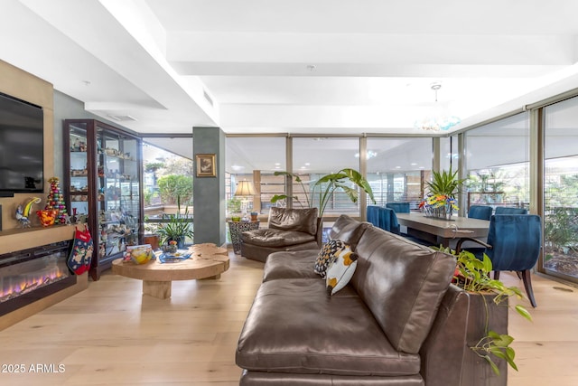 living room with light wood-type flooring, an inviting chandelier, and floor to ceiling windows