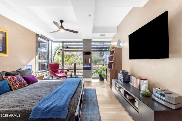 bedroom with floor to ceiling windows, ceiling fan, and light hardwood / wood-style floors