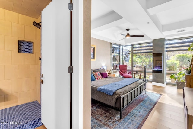 bedroom with light hardwood / wood-style flooring, a wall of windows, and ceiling fan