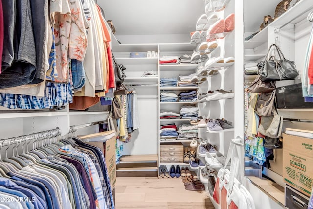 walk in closet with light hardwood / wood-style flooring