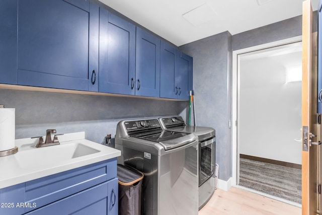 washroom featuring light hardwood / wood-style floors, sink, cabinets, and independent washer and dryer