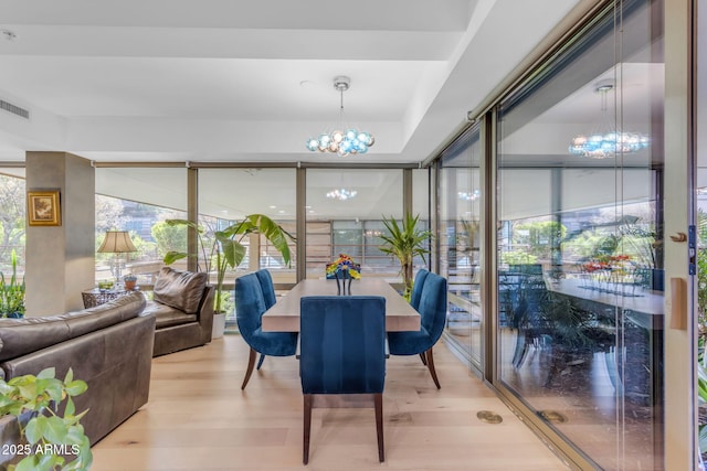 dining room with light hardwood / wood-style flooring and an inviting chandelier