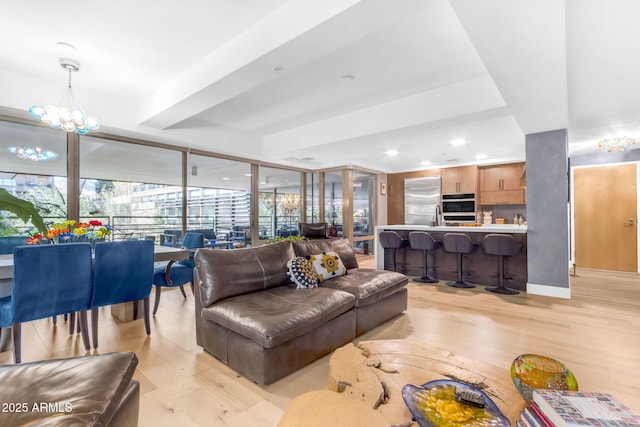 living room featuring light hardwood / wood-style flooring, expansive windows, and a notable chandelier