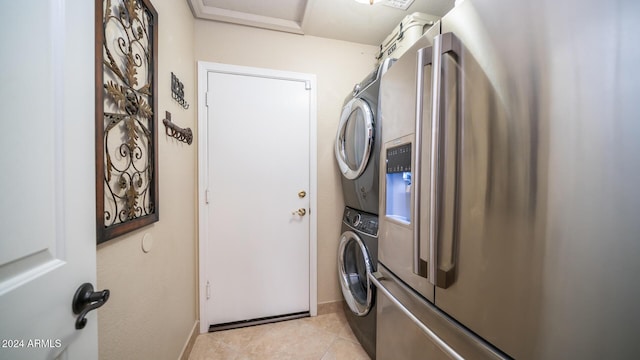 clothes washing area featuring light tile patterned floors and stacked washing maching and dryer