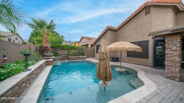 view of swimming pool with pool water feature and a patio