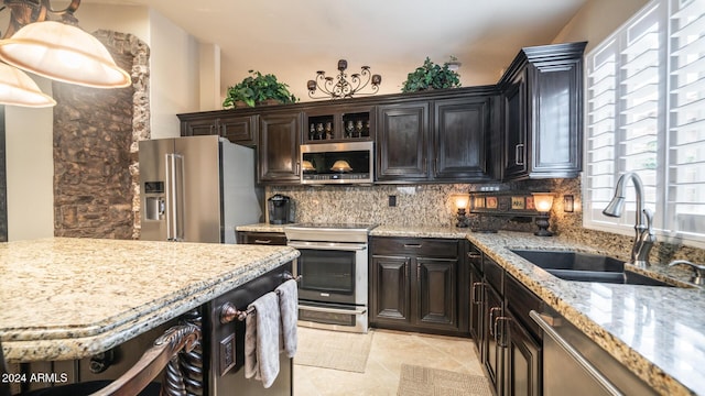 kitchen featuring decorative backsplash, dark brown cabinets, stainless steel appliances, sink, and light tile patterned flooring