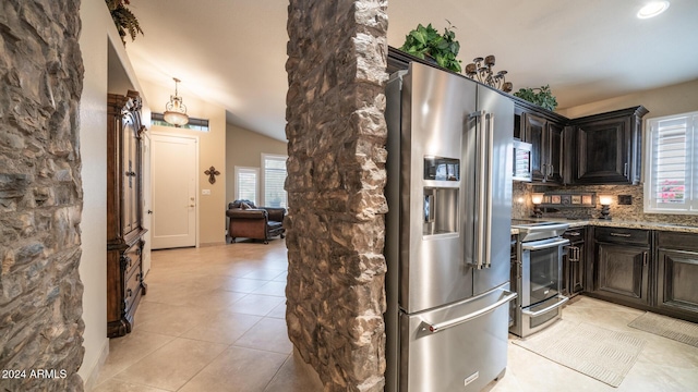 kitchen featuring light stone countertops, stainless steel appliances, backsplash, lofted ceiling, and light tile patterned floors