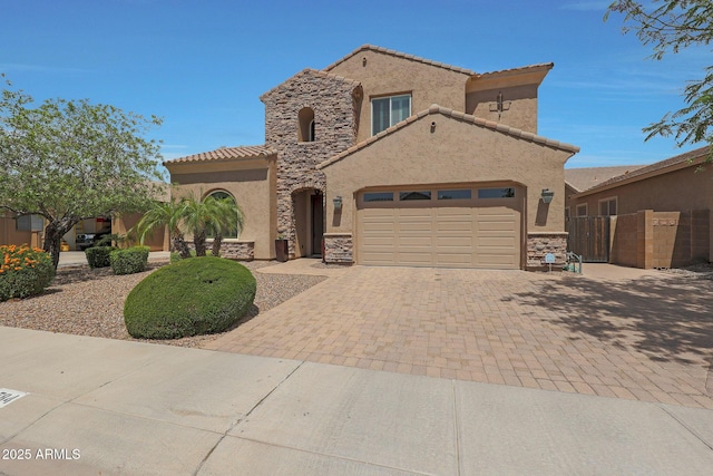 mediterranean / spanish-style house featuring stone siding, a garage, decorative driveway, and stucco siding