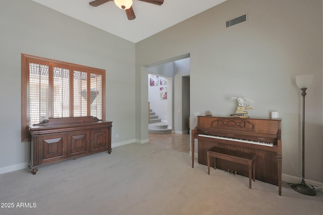 living area with a ceiling fan, carpet flooring, stairs, baseboards, and a towering ceiling