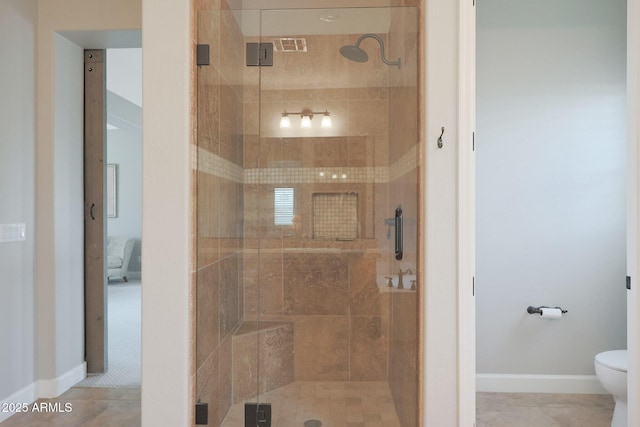 ensuite bathroom with a shower stall, toilet, baseboards, and tile patterned floors