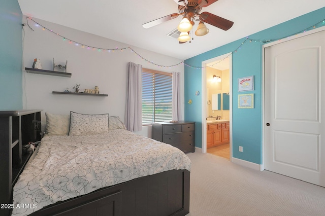 bedroom featuring light carpet, a sink, ensuite bathroom, a ceiling fan, and baseboards