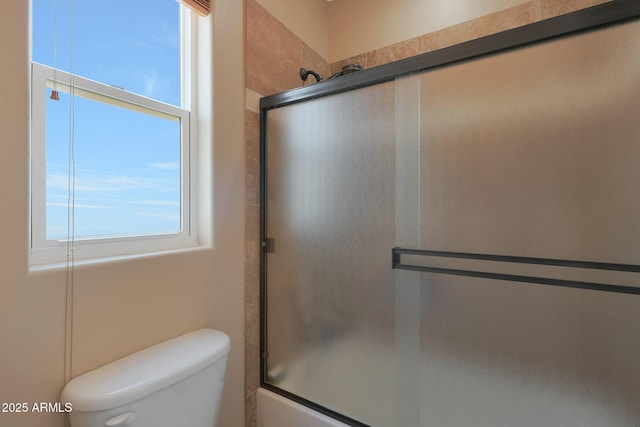 bathroom with toilet and bath / shower combo with glass door