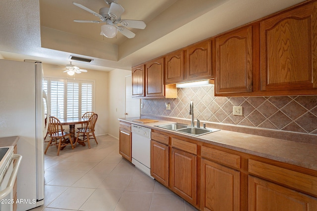kitchen featuring sink, white appliances, a tray ceiling, ceiling fan, and backsplash