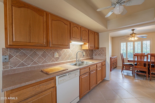 kitchen featuring tasteful backsplash, dishwasher, sink, light tile patterned floors, and a raised ceiling