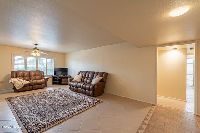 living room featuring ceiling fan, a textured ceiling, and light tile patterned floors