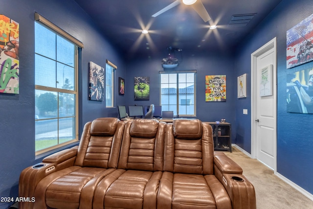 carpeted home theater with ceiling fan and plenty of natural light