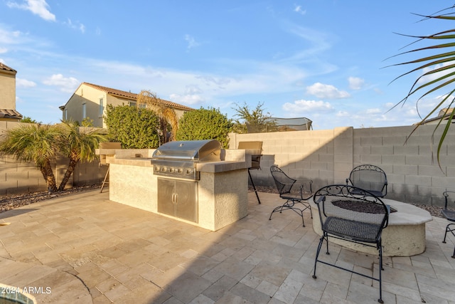 view of patio with exterior kitchen and a grill