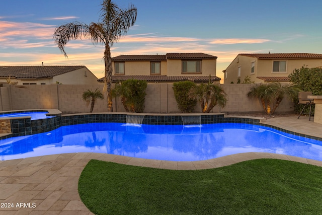 pool at dusk with an in ground hot tub, a patio, and pool water feature