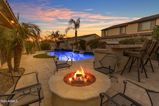 pool at dusk featuring an outdoor fire pit and a patio area