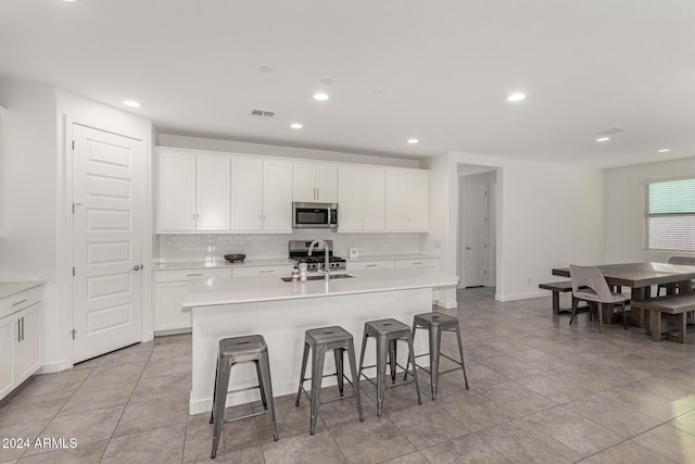 kitchen featuring sink, stainless steel appliances, a kitchen breakfast bar, a kitchen island with sink, and white cabinets