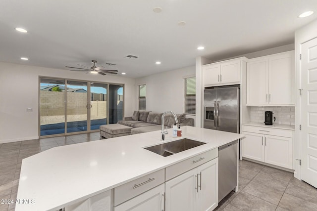 kitchen featuring decorative backsplash, appliances with stainless steel finishes, sink, white cabinetry, and an island with sink