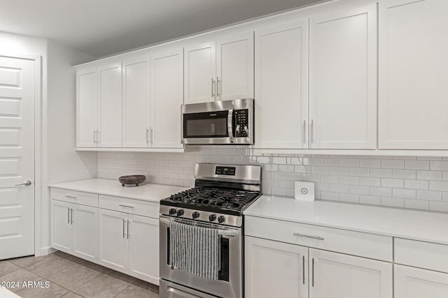 kitchen with light tile patterned floors, white cabinetry, appliances with stainless steel finishes, and tasteful backsplash