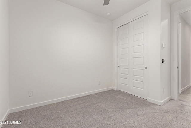 unfurnished bedroom featuring ceiling fan, light colored carpet, and a closet