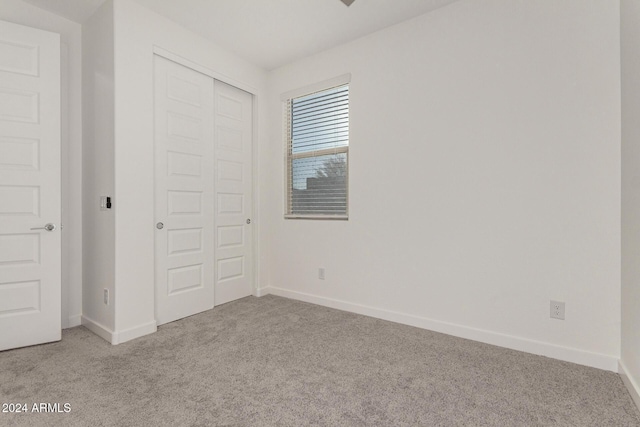 unfurnished bedroom with light carpet and a closet