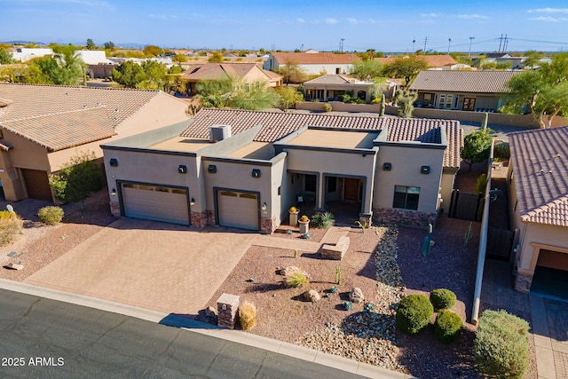 view of front of property featuring an attached garage, stone siding, decorative driveway, a residential view, and stucco siding