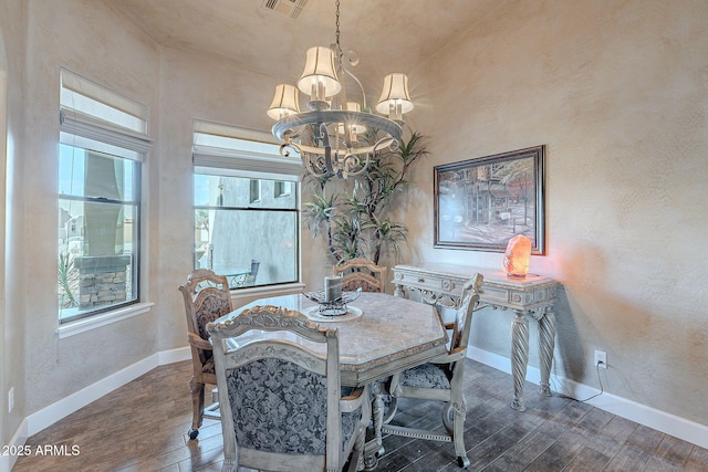 dining space featuring visible vents, a textured wall, hardwood / wood-style floors, an inviting chandelier, and baseboards