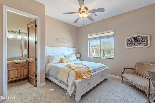 bedroom featuring light carpet, a sink, visible vents, baseboards, and ensuite bath