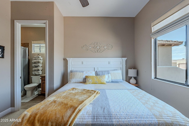 carpeted bedroom with ensuite bathroom and baseboards