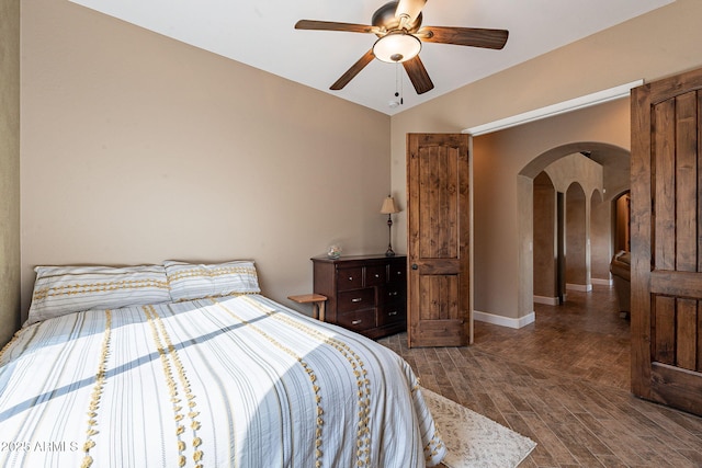 bedroom featuring arched walkways, ceiling fan, wood finished floors, and baseboards