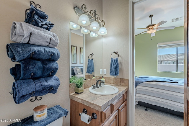 ensuite bathroom featuring ensuite bathroom, a textured wall, visible vents, a ceiling fan, and vanity