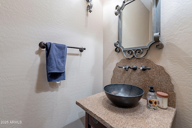 bathroom featuring a textured wall and vanity